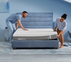man and woman placing a cloud mattress on their bed frame