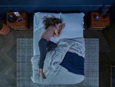 A woman asleep in bed in a styled room with a rug and two night stands