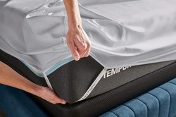 Detail shot of StayTight sheet corner straps being put onto a Tempur mattress