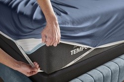 Indigo Rayon Bambo sheet set being put onto a Tempur-Pedic mattress, highlighting the StayTight corner straps