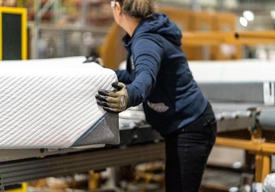 woman grabbing mattress in a factory