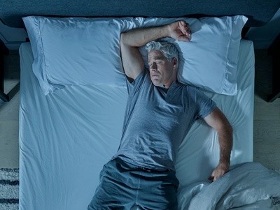 A man laying on his mattress, sleeping hot