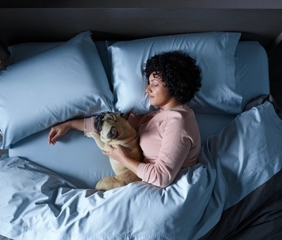 A woman sleeping cuddling her dog