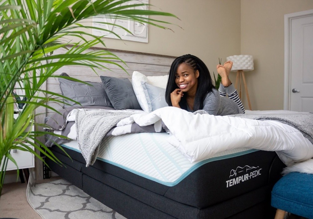 A smiling woman on a Tempur-Pedic mattress