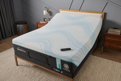 An overhead shot of a Tempur-Pedic mattress on a slightly-raised adjustable base with the remote on the bed in a styled room