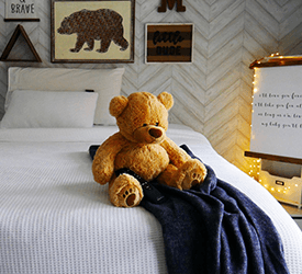 A teddy bear sitting on a Tempur-Pedic mattress