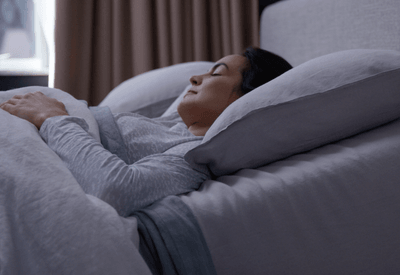 A woman slightly elevated sleeping on an adjustable base.