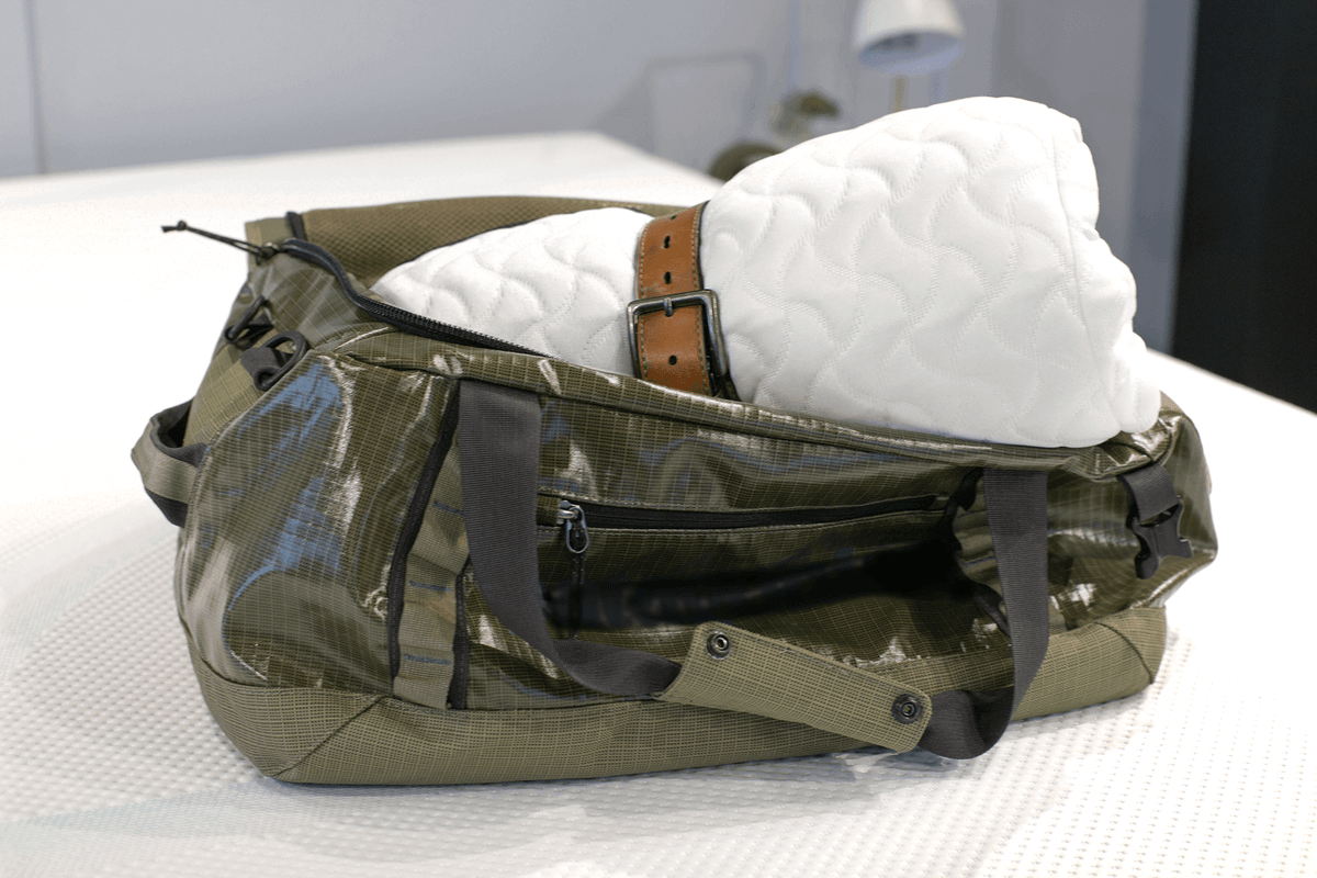 Tempur-Cloud Pillow rolled up tied with belt laying diagonally in green duffle bag