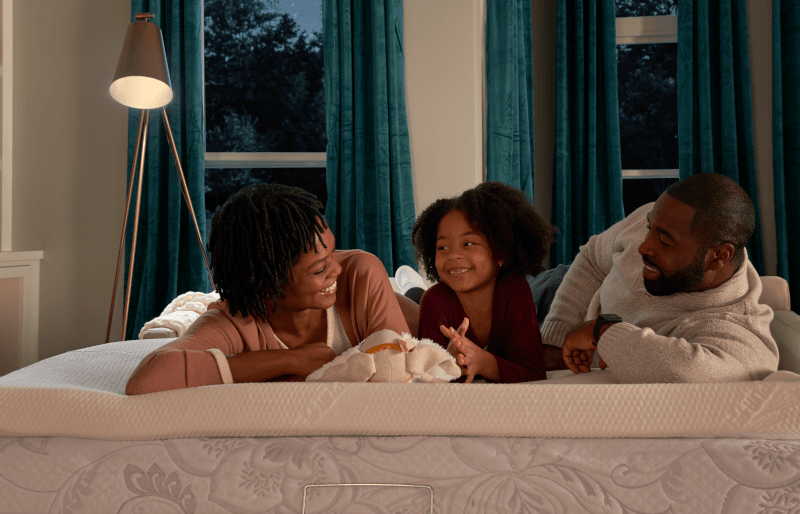 Family lying on mattress topper on pull out couch smiling