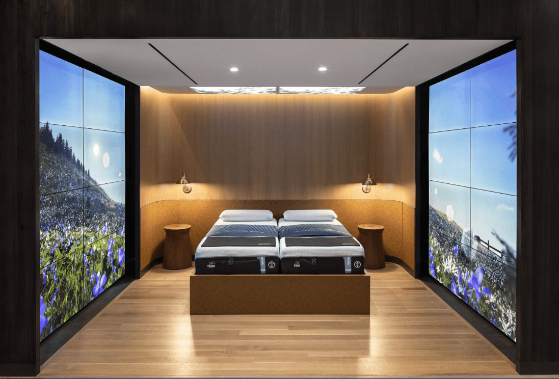 Tempur-Pedic flagship store split king bed on display with screens surrounding room with purple flowers showing