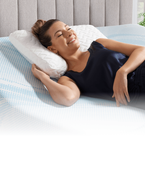 woman smiling on mattress with pillow