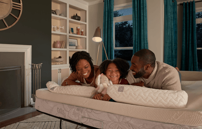 Family of three lying on mattress with mattress topper smiling