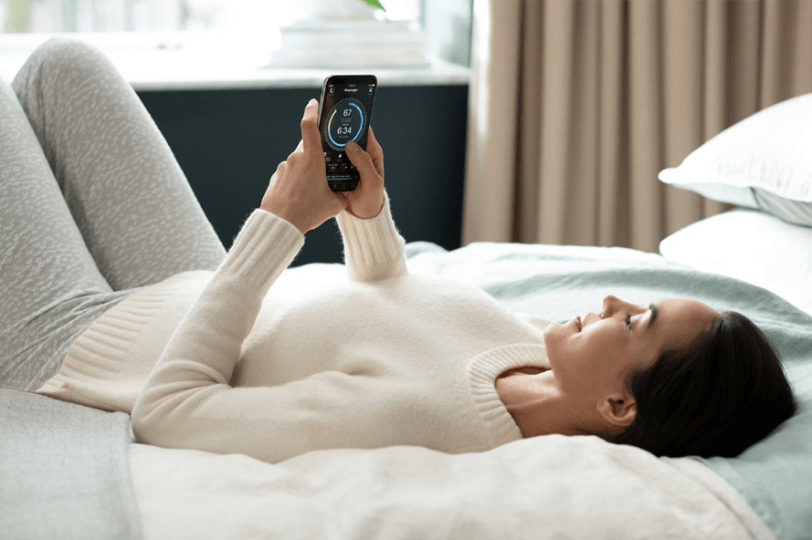 a woman laying on mattress looking at her SleepTracker App