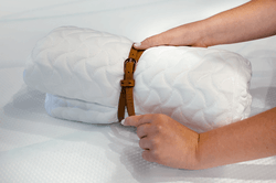 A rolled Tempur-Cloud pillow being secured with a belt