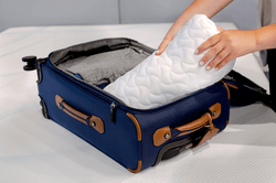 A rolled Tempur-Cloud pillow being packed into a travel bag